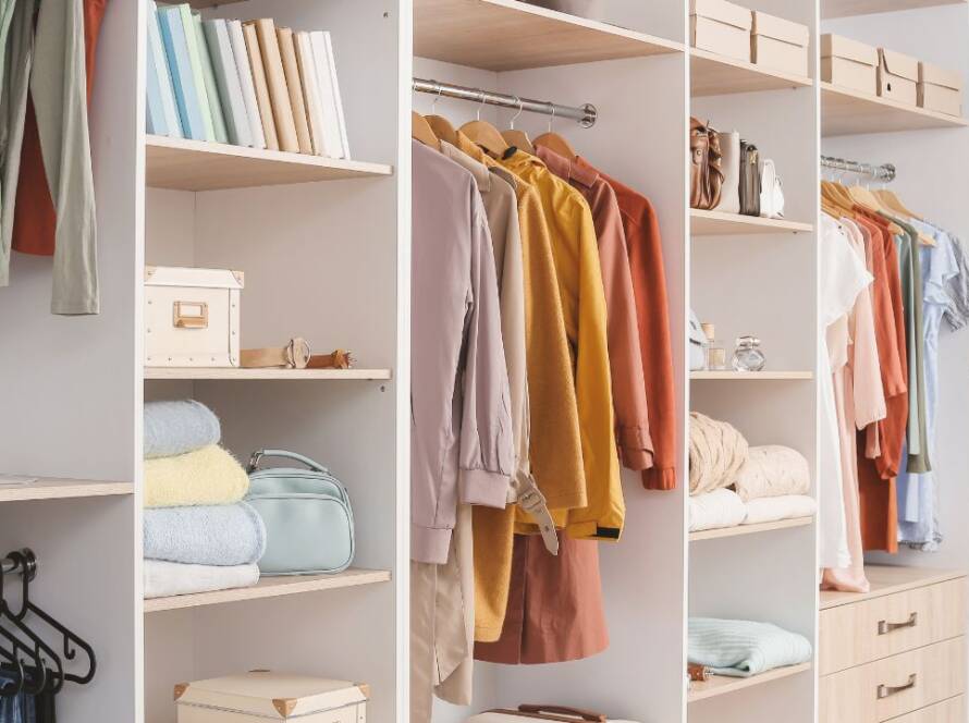 A beautifully organized closet with clothes neatly folded and hung, featuring stylish storage solutions and a touch of personality.